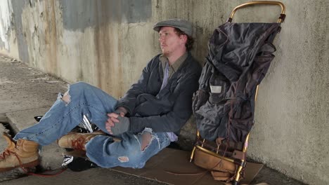 Profile-Shot-of-a-Young-Adult-Homeless-Man-Sitting-on-the-Sidewalk-with-Despair-in-his-Eyes