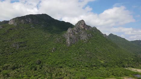 imágenes aéreas hacia esta montaña de piedra caliza que revelan salinas y cocoteros, hermoso cielo azul y nubes