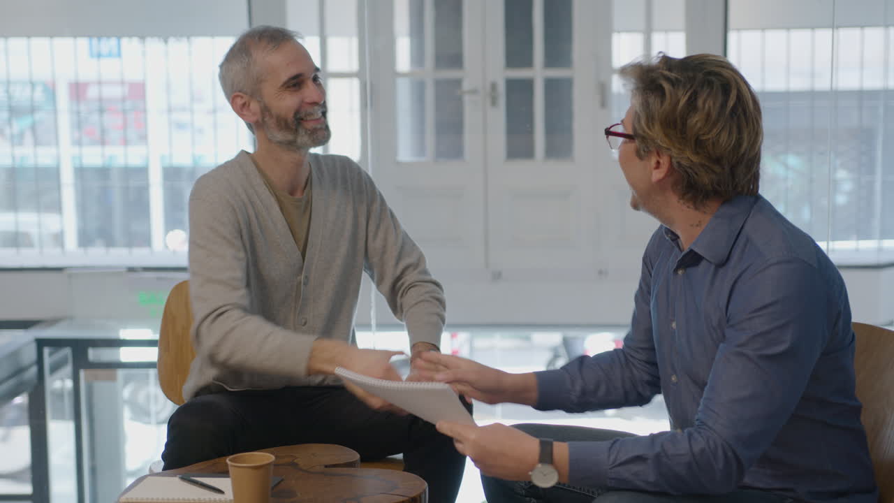 Mature Businessmen Discussing Project and Shaking Hands in Office