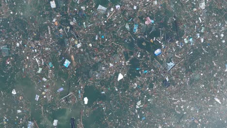 Low-altitude-top-down-drone-shot-of-polluted-water-filled-with-trash-floating-over-dead-coral-reef-in-the-turqouise-tropical-water-of-Bali-Indonesia