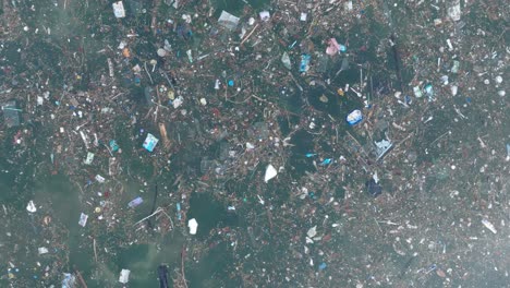fotografía de avión no tripulado de baja altitud de arriba hacia abajo de agua contaminada llena de basura flotando sobre arrecife de coral muerto en las aguas tropicales turquesa de bali, indonesia