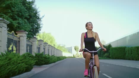 Mujer-Delgada-En-Ropa-Deportiva-Montando-En-Bicicleta-Mientras-Entrena-En-El-Parque-De-Verano