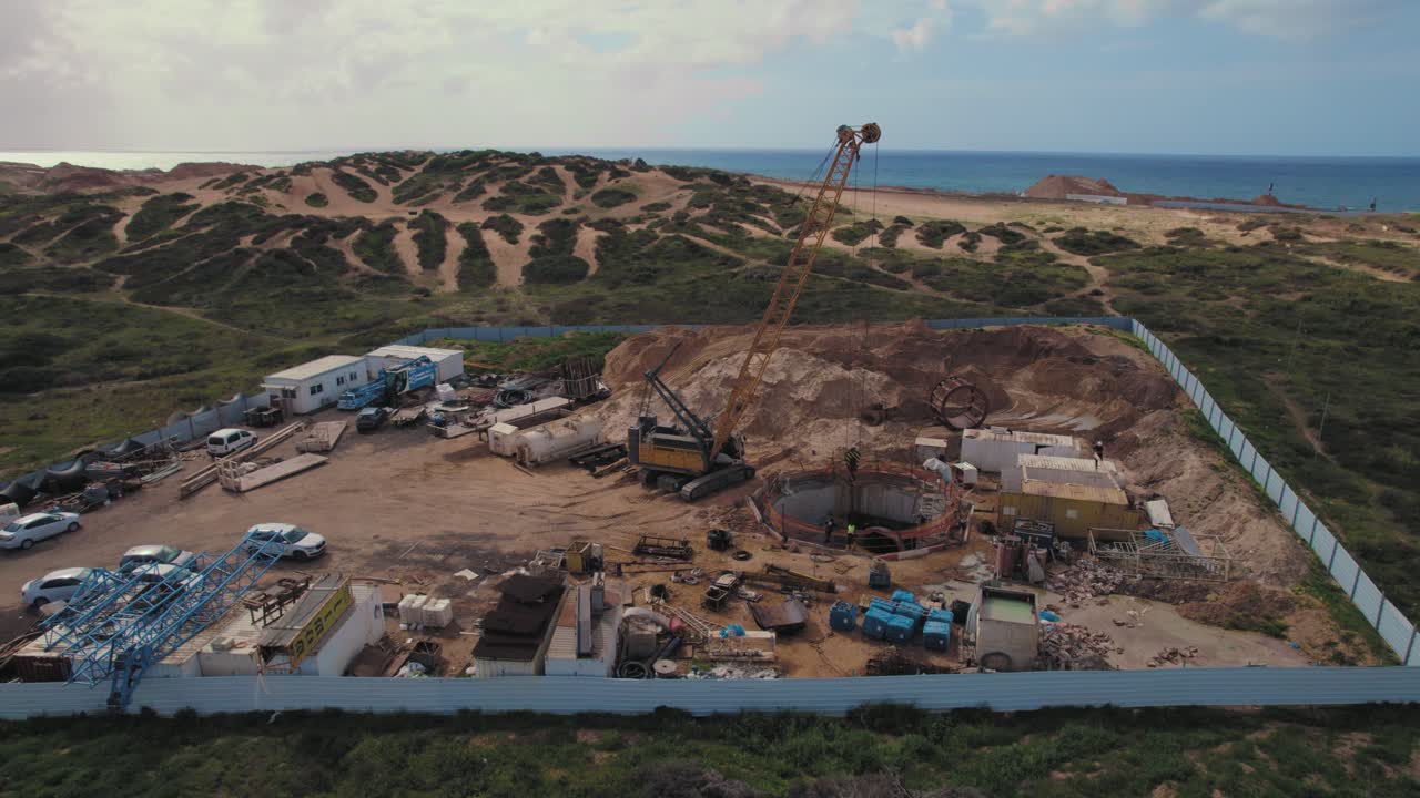 excavación en el suelo por una grúa sobre orugas para reparar una tubería de alcantarillado subterráneo con personas dentro del agujero