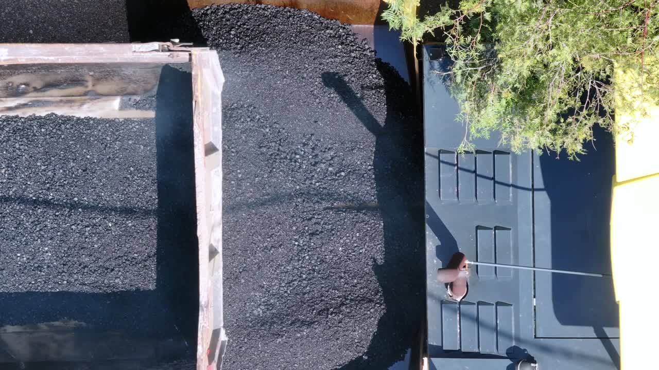 Aerial shot 4k footage while truck pouring asphalt on asphalt machine