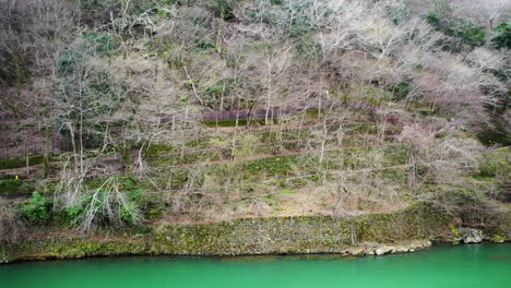 Seguimiento-De-La-Toma-De-Drones-De-Una-Persona-Que-Anda-En-Bicicleta-A-Lo-Largo-Del-Río-En-Kioto,-Japón