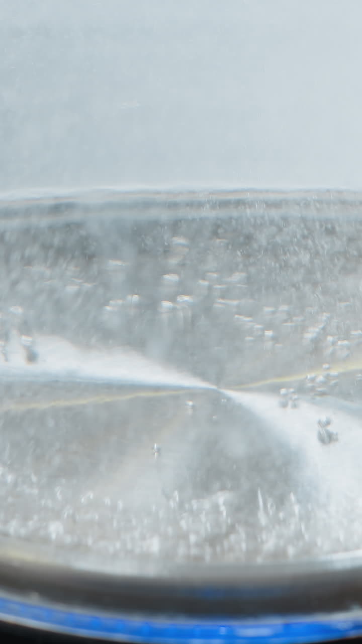 거품이 상승하는 투명한 항아리에 있는 는 물의 클로즈업, 물 보일러에서 가열 과정을 보여주는, 물 수준과 거품이 명확하게 보입니다.