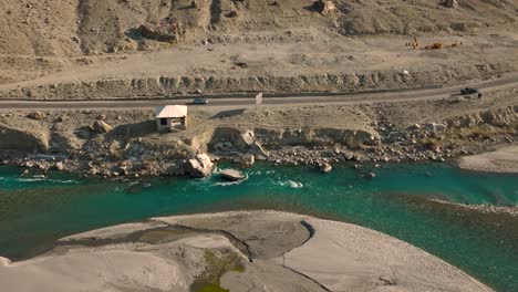 Turquoise-blue-water-of-Ghizer-river-flowing-through-forest-in-Gahkuch-surrounded-by-Hindu-Kush-mountain-range