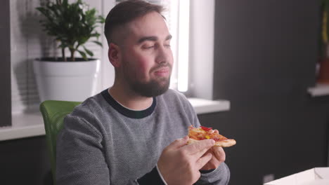 homem faminto descansando e comendo pizza saborosa no escritório 2