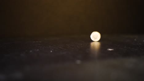 Spinning-a-nickel-of-US-Currency-on-a-table-in-low-light