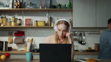 woman accountant working remotely sitting at kitchen with headphones close up.