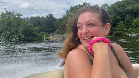 a young woman on a speedboat with her hair in the wind excited, thrilled, and happy to be out on the lake