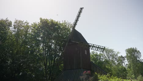 Hölzerne-Windmühle,-Die-An-Einem-Sonnigen-Tag-In-Zeitlupe-In-Einem-Wald-Steht