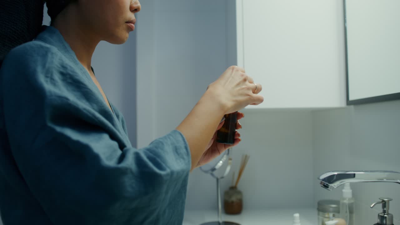 浴室で顔に血清を塗っている女性