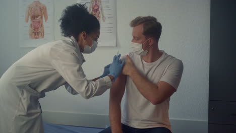 man patient getting covid19 vaccine in clinic close up. nurse making injection