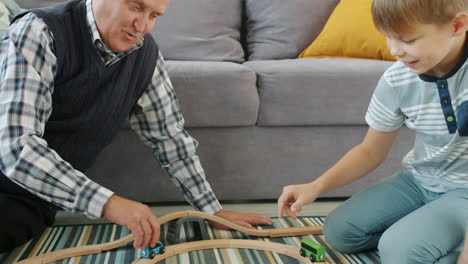 grandfather and grandson playing with wooden train set