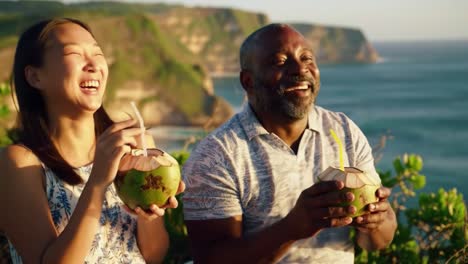 enjoying refreshing coconut drinks with a breathtaking ocean view: a joyful moment captured between two friends sharing laughter and delight in nature's embrace