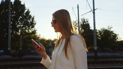 attractive woman walking along train station platform uses the phone steadicam shot