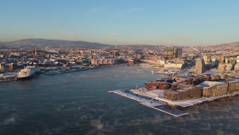 Goldene-Stunde-Blick-über-Bjorvika-Im-Stadtteil-Sentrum-Von-Oslo,-Norwegen-Mit-Nebel,-Der-über-Dem-Wasser-Schwebt