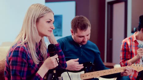 company of merry friends sing songs into the microphone and play the guitar at home