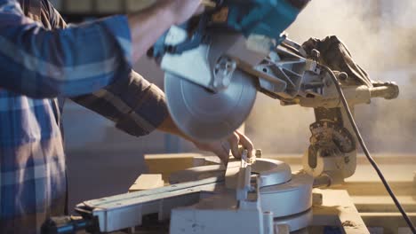 The-carpenter-cuts-wood-with-a-circular-saw-at-sunset.