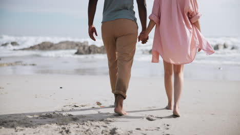 couple walking hand in hand on a sandy beach