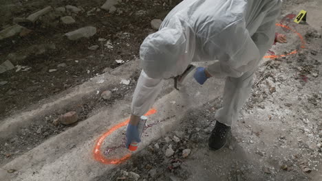 el científico forense pinta una marca de rociado naranja alrededor
