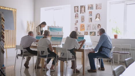 like senior friends attending together at a painting class. small group taking a variety of fun classes together. a group of elderly people attend a master class on drawing together spending time.