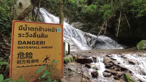 warning sign at waterfall in lush jungle