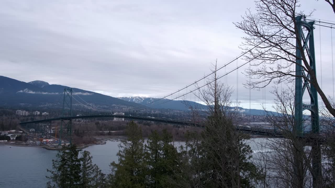 Traffic moving over suspension bridge on a cloudy winter day (4K)