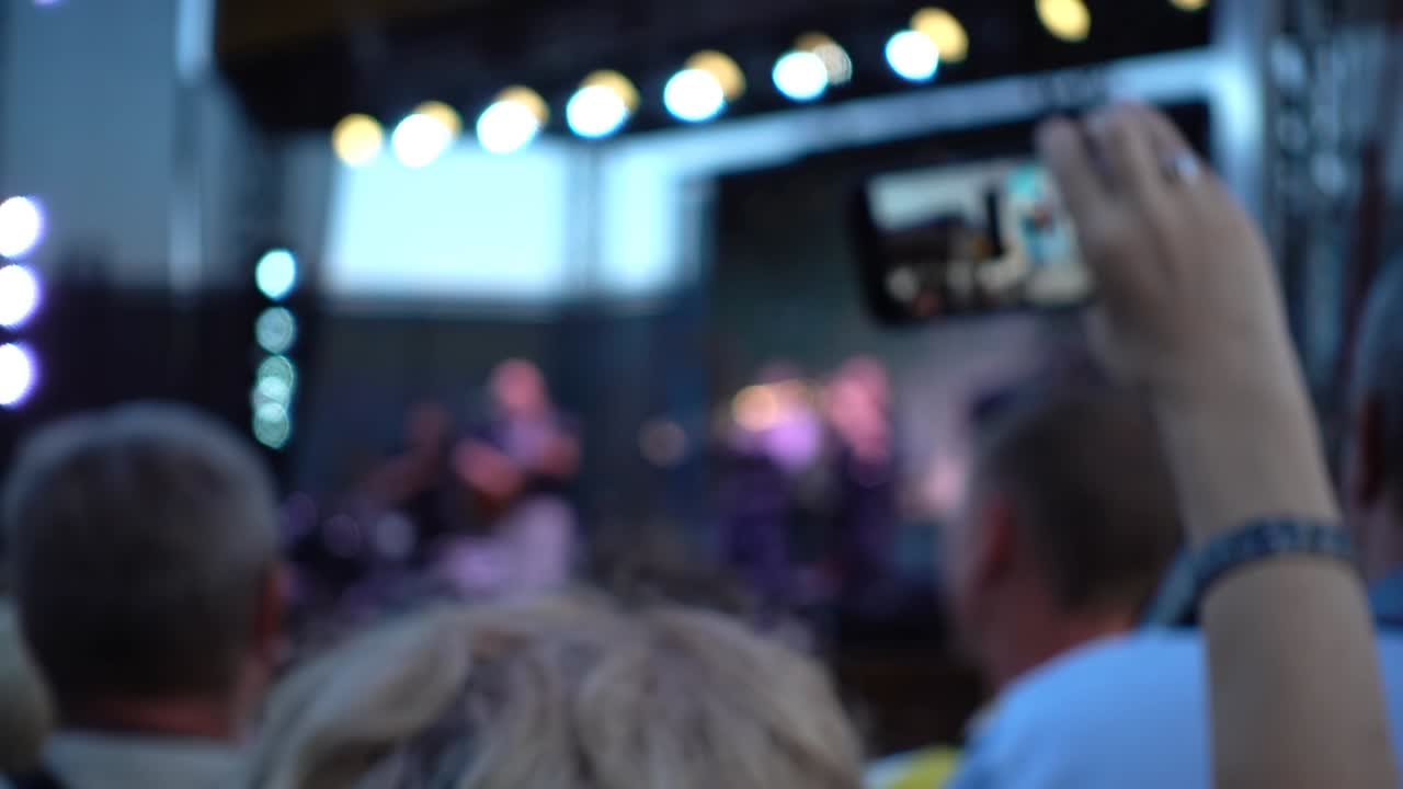 Concert on the stage. Crowd of people and musicians on the scene. Out of focus