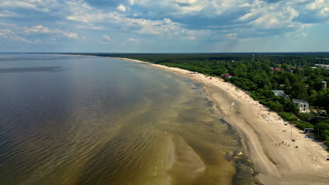 Aerial-view-of-Jūrmala-beach-in-Latvia-on-a-sunny-day,-with-people-enjoying-the-sun