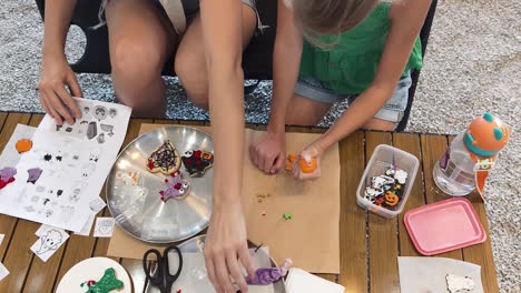 mother and daughter decorating halloween cookies