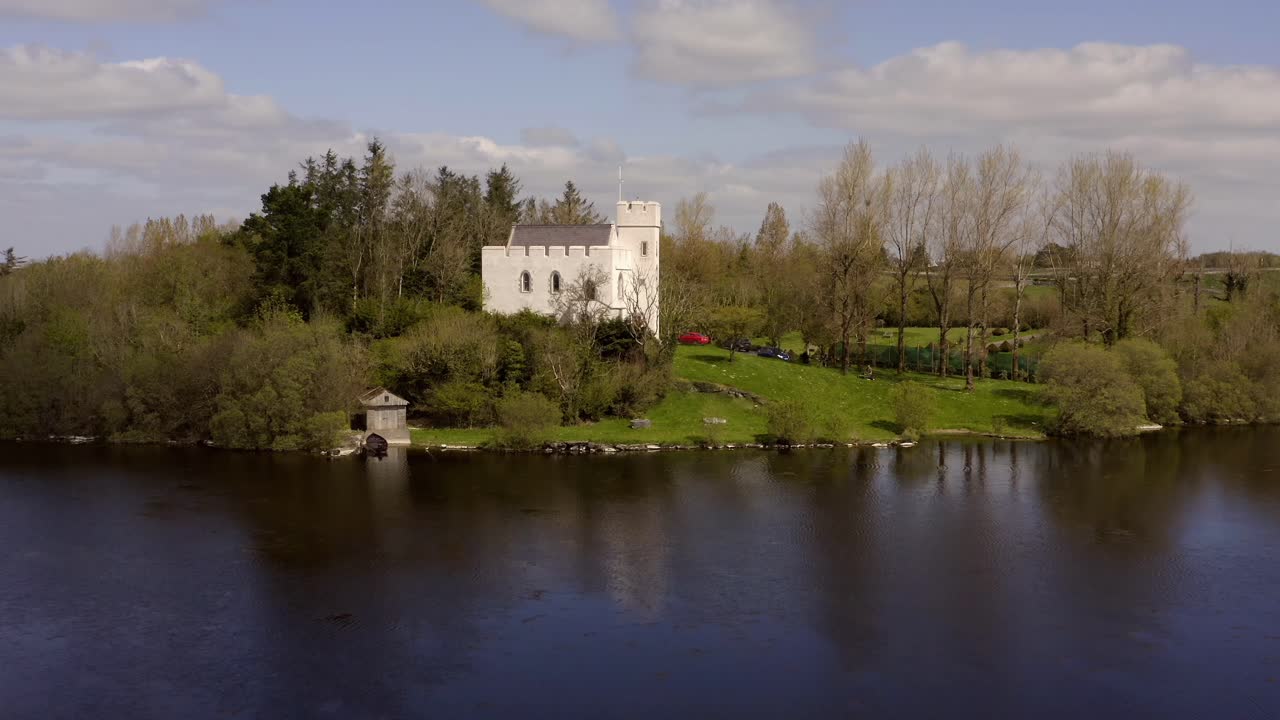 작은 색 요새가 숲에서 조용한 호수를 내려다보고 있습니다.