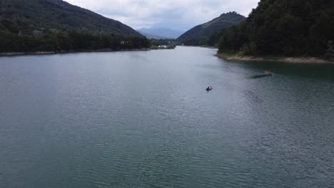 Toma-Aérea-De-Un-Grupo-De-Amigos-Divirtiéndose-En-Un-Día-Soleado-Con-Barcos-En-El-Tranquilo-Lago-Paltinu-Del-Valle-De-Doftana-En-Rumania.