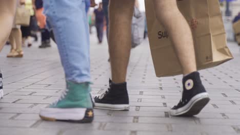 feet walking on the sidewalk in the street.