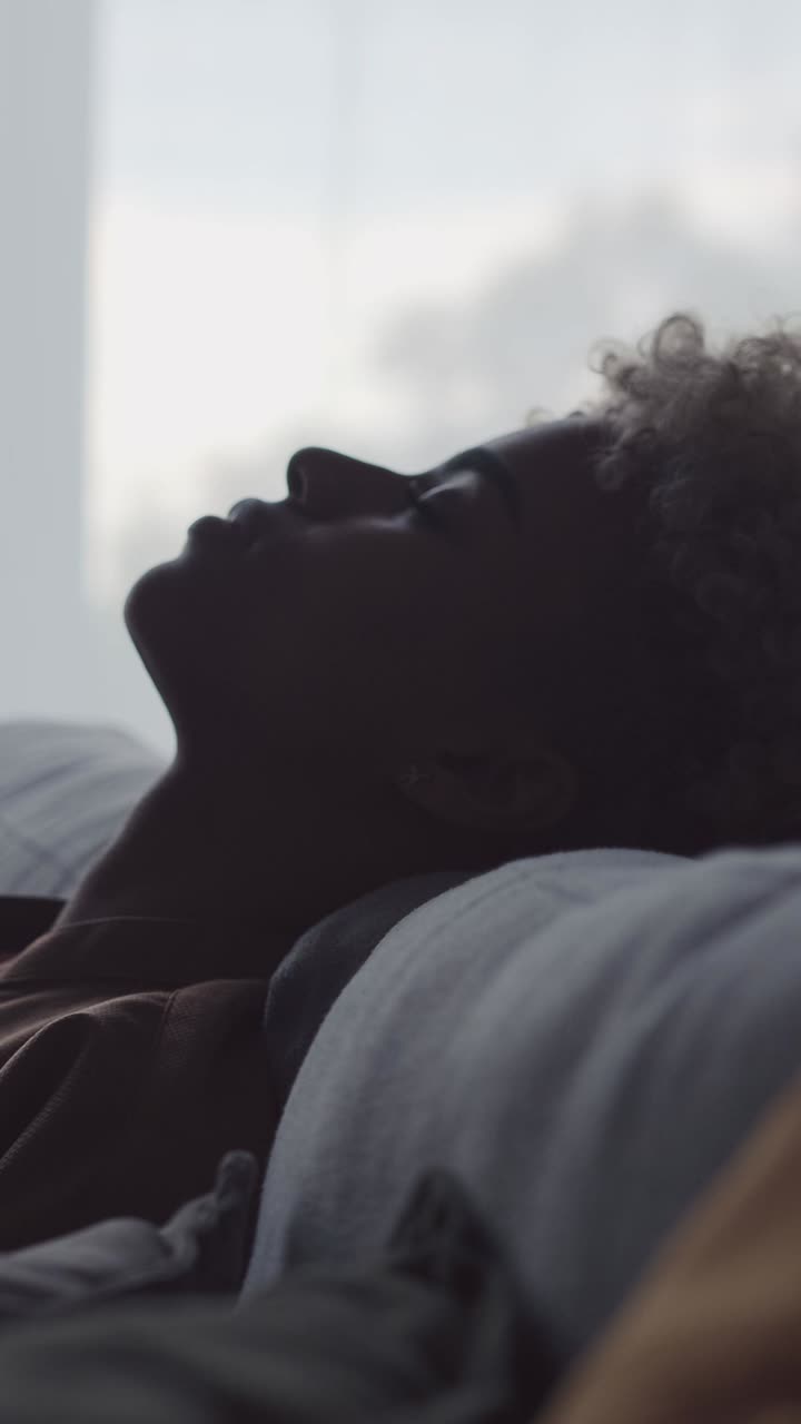 Jovem mulher afro-americana, cansada e relaxada, se recosta no sofá