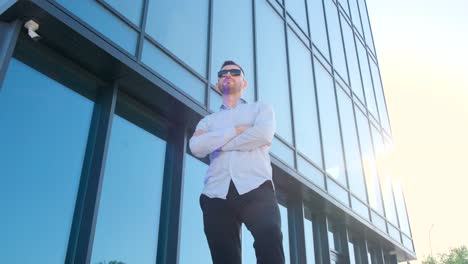 a man stands in front of a tall building with a facade made of composite materials such as metal and