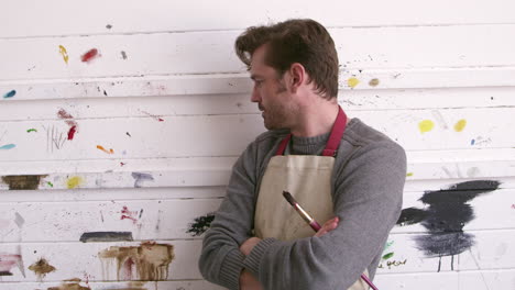 male artist leaning against paint covered wall shot on r3d