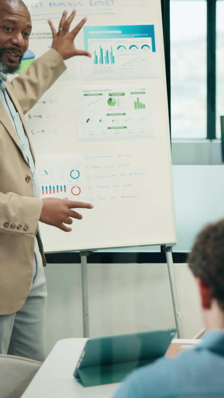 Mature Businessman Presenting Sales Data to Colleague in Office