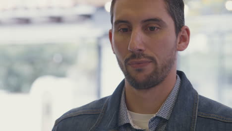 medium shot of a smiling man trying a sample of ice cream in a modern ice cream parlor. the background is out of focus, highlighting his expression of enjoyment and surprise.
