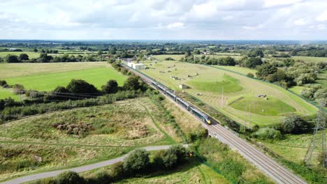 train driving along tracks in countryside through fields, sunny day