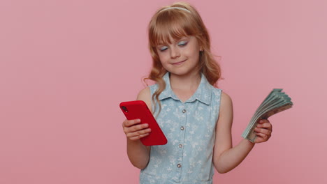 smiling happy child girl use smartphone rejoicing win, receiving money dollar cash lottery jackpot
