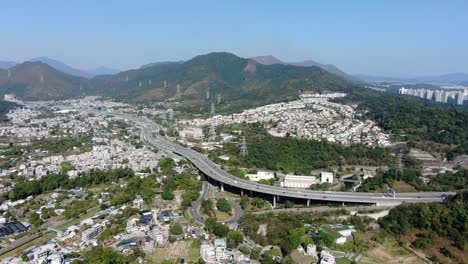 vista aérea de la zona residencial de las afueras de hong kong, con la autopista de conexión y las laderas de las montañas circundantes