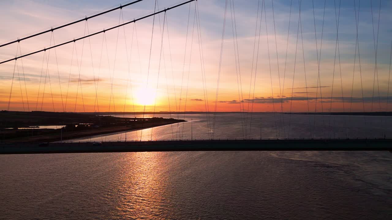 Humber Bridge at golden hour: a serene pathway for cars captured in an aerial drone's lens beneath the setting sun