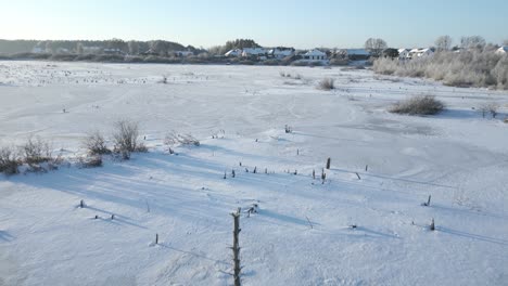 flying low over a snow-covered lake towards a small town in the distance