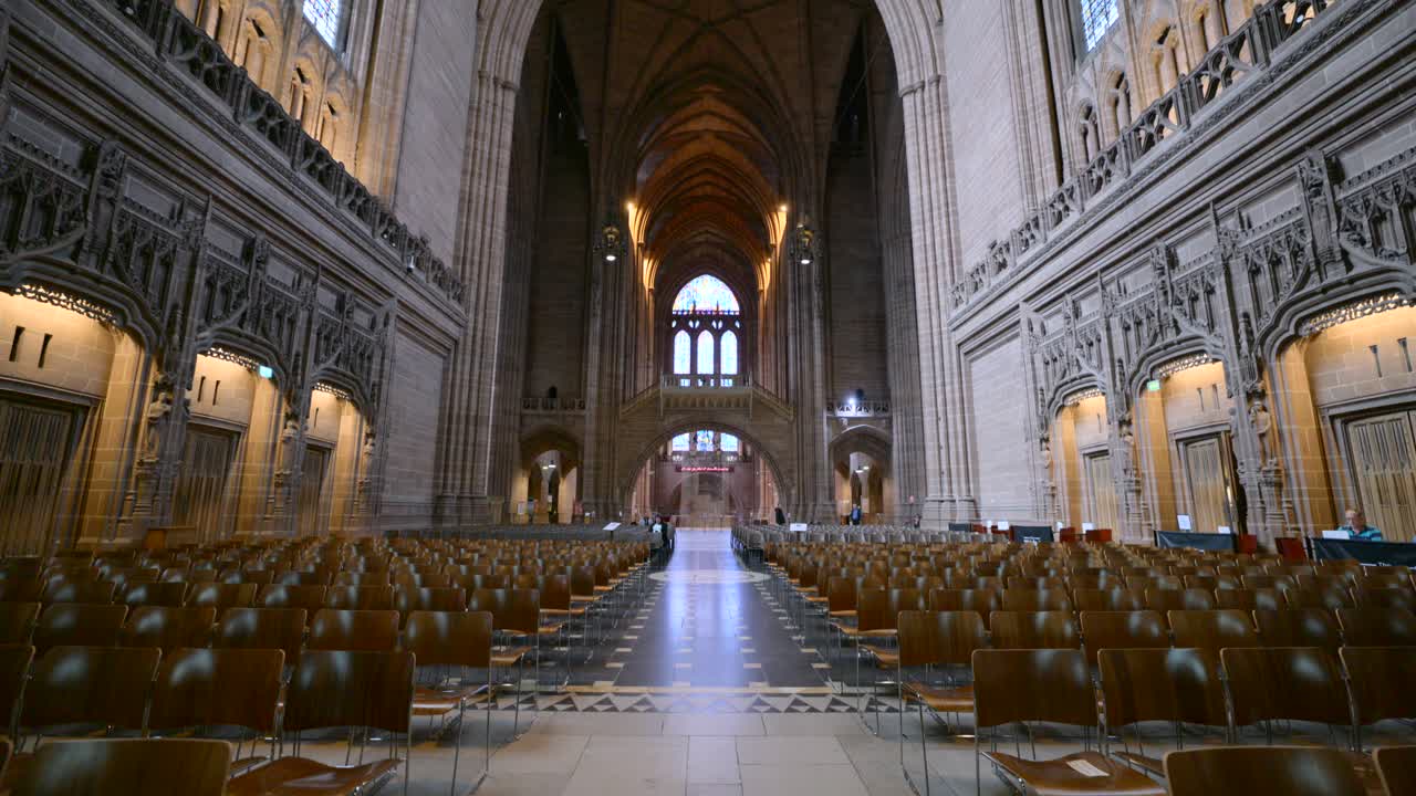 Wide angle view of the nave and altar inside Liverpool Cathedral, highlighting its gothic revival architecture and colorful stained glass