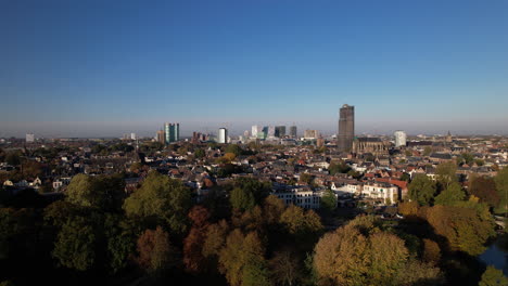 Autumn-colors-in-the-Lepelenburg-park-trees-with-the-cityscape-of-Utrecht-in-the-background-where-the-scaffolded-church-tower-rises-above-the-urban-Dutch-city