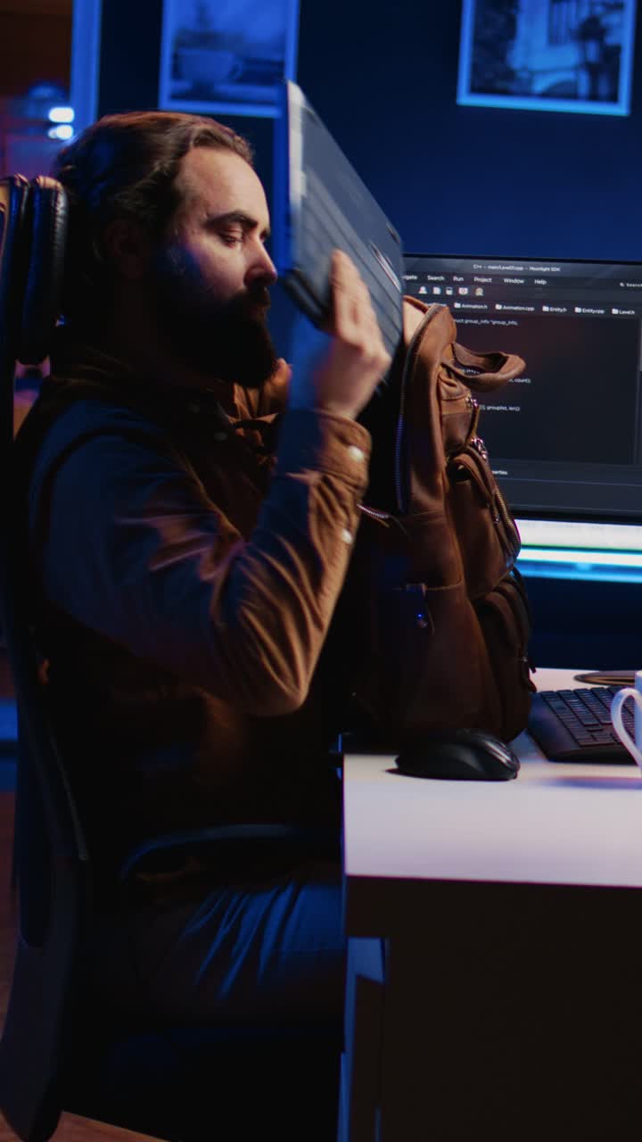 Programmer Closing Laptop and Packing Up After Working Late