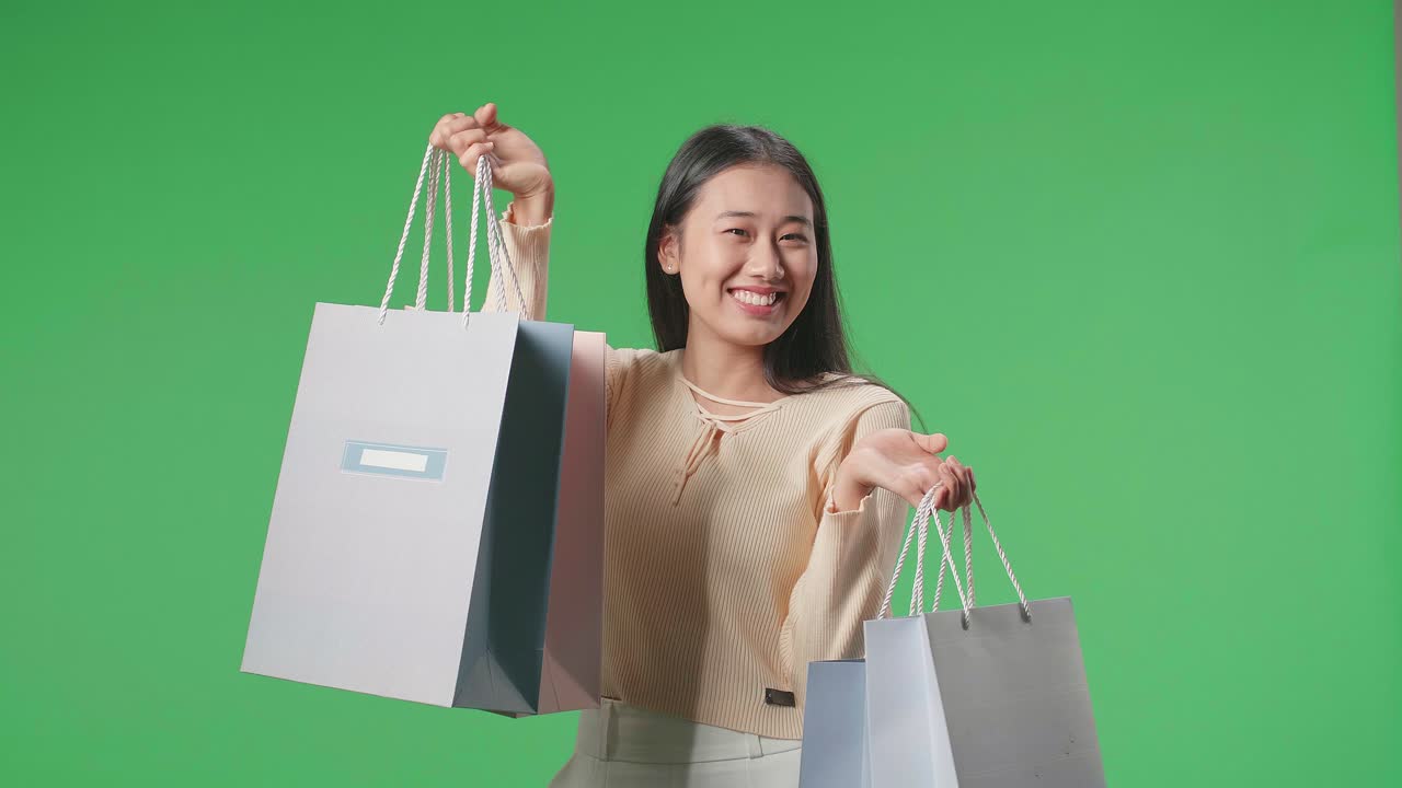 An Asian Shopping Woman With Shopping Bags Smile To Camera While Standing In Front Of Green Screen