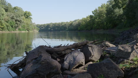 rocks on the riverbank with trees reflected in the water